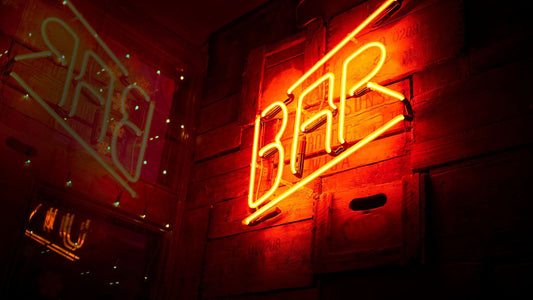 Neon sign on a brick wall saying 'BAR'